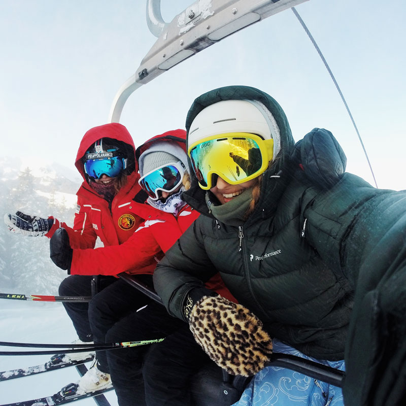 Three women skiers smiling in chairlift selfie photo