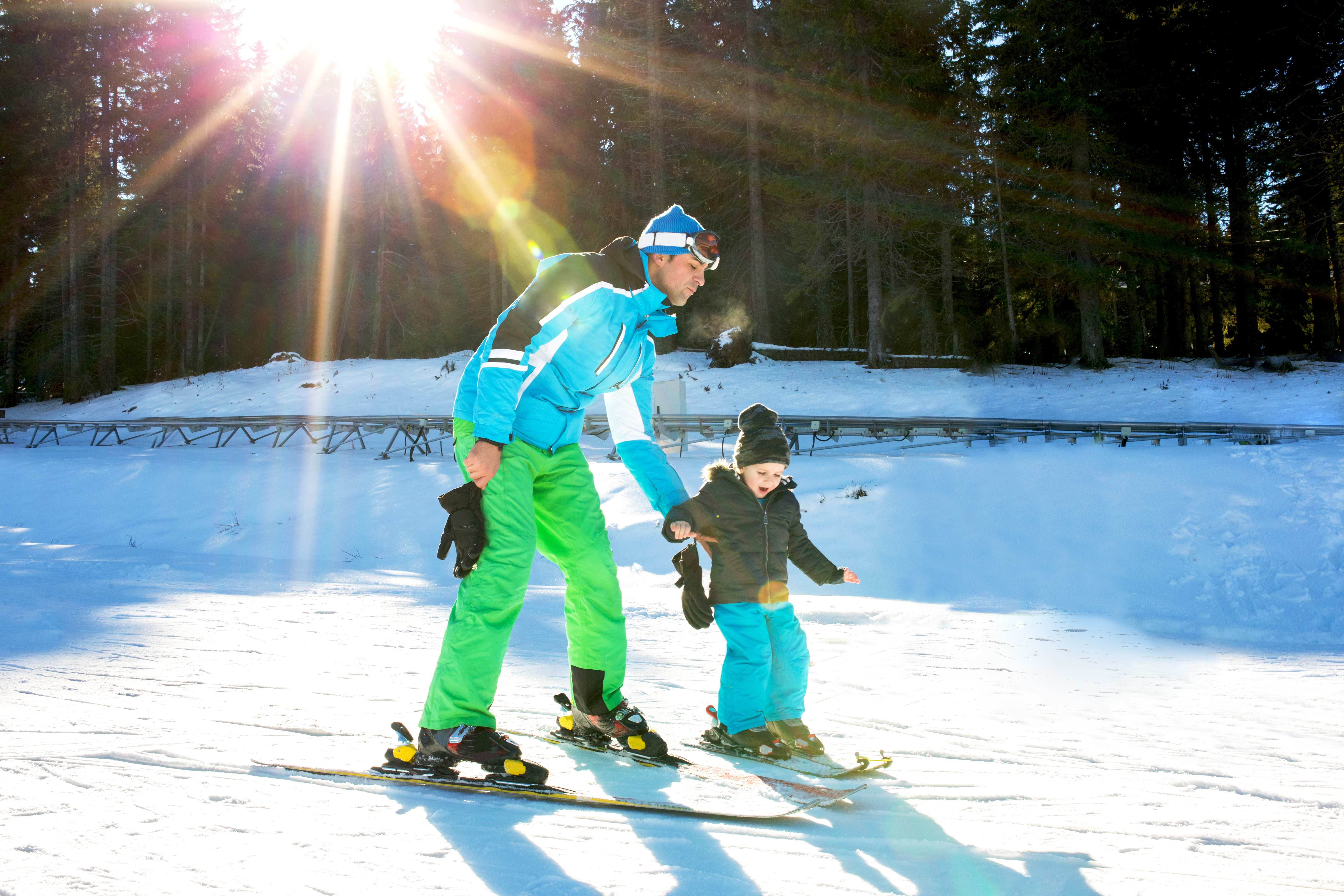 Ski trainer teaching kid to ski while spending day on a mountain.