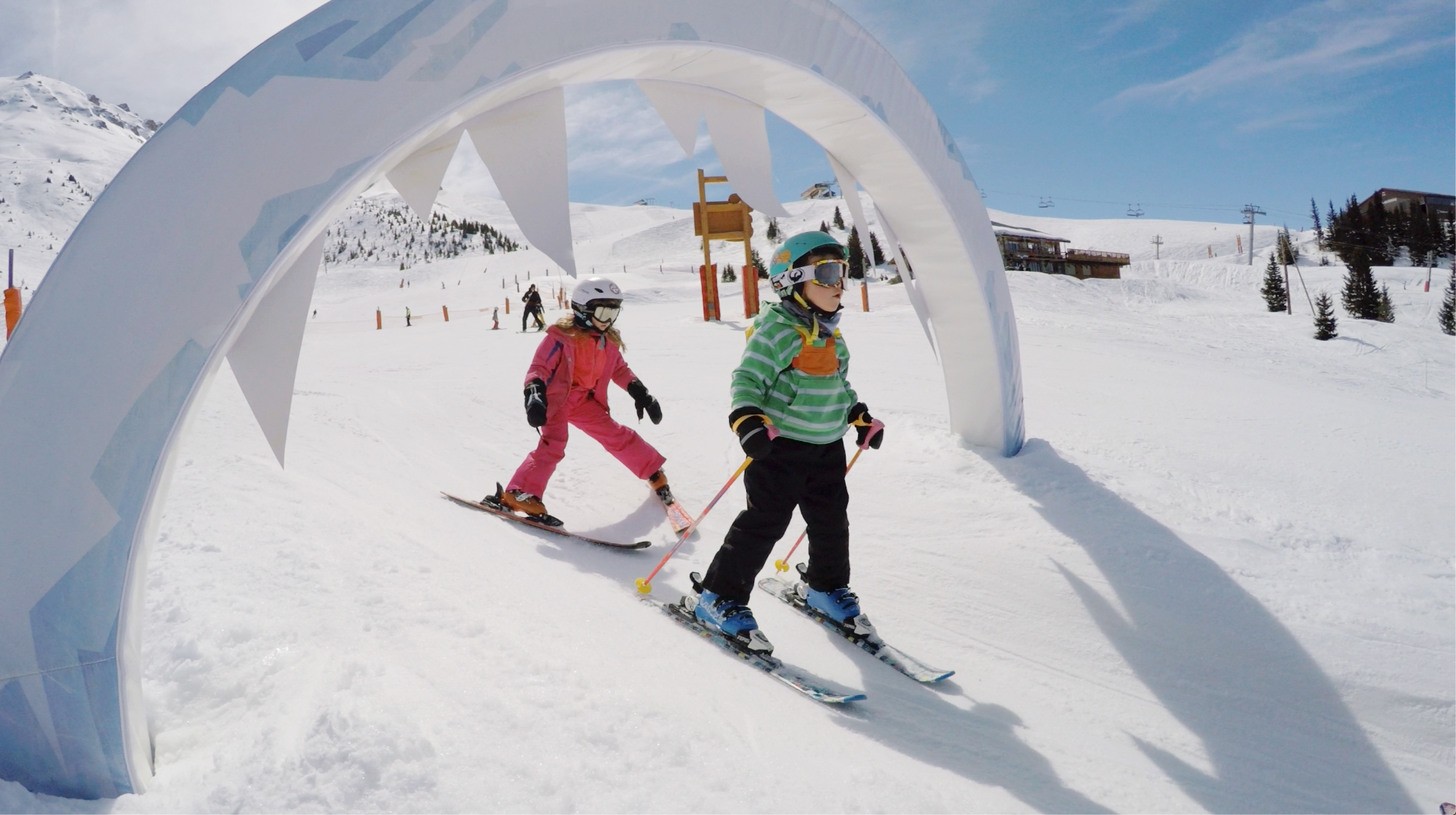 two children having fun skiing under an arch during ski lessons